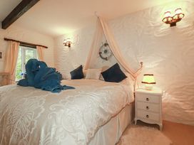 A bedroom with a bed and nightstand at Poldark Cottage East Taphouse