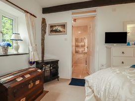 A bedroom with a window and a door leading to a bathroom at Poldark Cottage East Taphouse