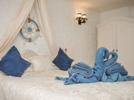 A bedroom with decorative towel swans on bed at Poldark Cottage East Taphouse