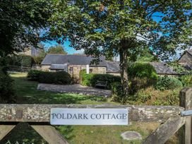 A cottage with a pathway and bench surrounded by trees at Poldark Cottage East Taphouse