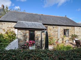 An outdoor view of a stone cottage with flowers by the window at Poldark Cottage East Taphouse