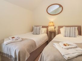 A bedroom with two beds and a bedside table with a lamp at The Hayloft in Northop near Chester