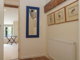 A hallway with a mirror and framed paintings at The Hayloft in Northop near Chester