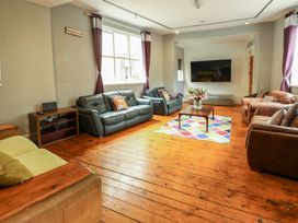 A living room with multiple sofas a wooden floor a coffee table with flowers and a mounted television at Mountain View in Penmaenmawr