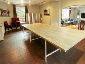 A large table in a room with stacked red chairs and a window showing outside at Mountain View in Penmaenmawr