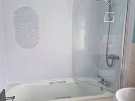 A bathroom with a bath tub and shower at Ty'r Enfys Bach - Upper Trearddur Bay
