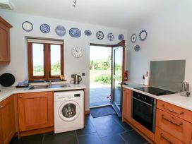 A kitchen with a washing machine, sink, and door at Pound Cottage in Huntshaw near Great Torrington