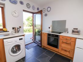 A kitchen with appliances and a door to the outside at Pound Cottage in Huntshaw near Great Torrington