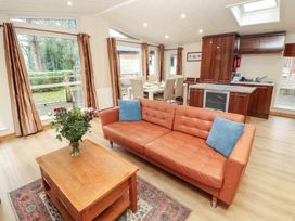 A living room with a sofa, coffee table, and dining area at Beech Hill Lodge (Beech Hill 9) at Fallbarrow Park