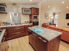 A kitchen with an island, stove, and sofa at Beech Hill Lodge (Beech Hill 9) at Fallbarrow Park, Bowness-on-Windermere