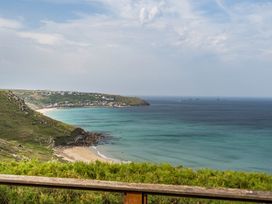 A view of a beach and sea with cliffs and houses at Cragford in Sennen Cove