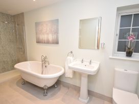 A bathroom with a clawfoot bathtub pedestal sink toilet and window with a vase of flowers at Lavender Cottage in Market Weighton