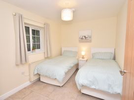 A bedroom with two single beds a nightstand with a lamp and a window at Lavender Cottage in Market Weighton