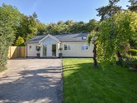 A single-story house with a driveway and lawn surrounded by trees at Lavender Cottage in Market Weighton