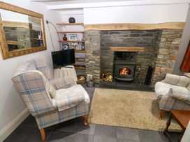 A living room with a fireplace and armchairs at Milk Wood Cottage in Laugharne