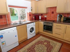 A kitchen with appliances and a window at Milk Wood Cottage in Laugharne