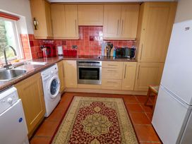 A kitchen with appliances and a rug at Milk Wood Cottage in Laugharne