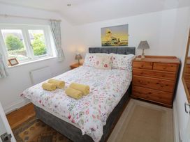 A bedroom with a bed and dresser at Milk Wood Cottage in Laugharne