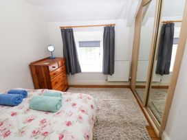 A bedroom with a bed and dresser at Milk Wood Cottage in Laugharne