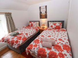 A bedroom with two beds and a bedside table at Milk Wood Cottage in Laugharne