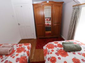 A bedroom with two beds and a wardrobe at Milk Wood Cottage in Laugharne