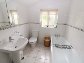 A bathroom with a sink, toilet, and bath tub at Milk Wood Cottage in Laugharne