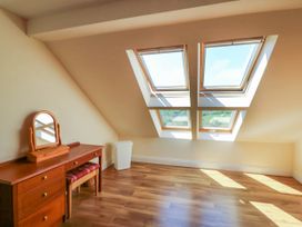 A room with wooden floor a wooden dresser with mirror a stool and four skylight windows at Curraha in Lauragh County Kerry