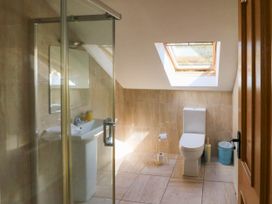 A bathroom with a glass shower enclosure a pedestal sink a toilet and a skylight window at Curraha in Lauragh County Kerry