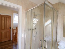 A bathroom with a glass shower enclosure wooden door and staircase outside at Curraha in Lauragh County Kerry