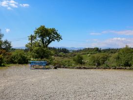 A gravel area with a blue picnic table and trees in the background at Curraha in Lauragh County Kerry