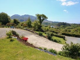 An outdoor garden area with bushes and flowers overlooking mountains and a gravel path at Curraha in Lauragh County Kerry