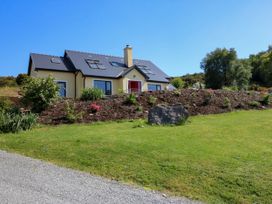 A house with a sloped roof and multiple skylights surrounded by a landscaped garden and grass at Curraha in Lauragh County Kerry