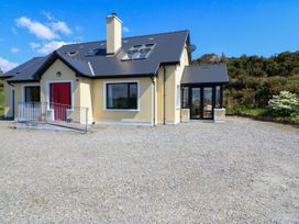 A detached house with a red front door and multiple windows on a gravel driveway at Curraha in Lauragh County Kerry