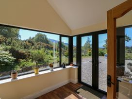 A sunroom with large windows and potted plants on the windowsill with a wooden door and a doormat at Curraha in Lauragh County Kerry