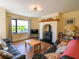 A living room with leather sofas wooden coffee table and a wood burning stove at Curraha in Lauragh County Kerry