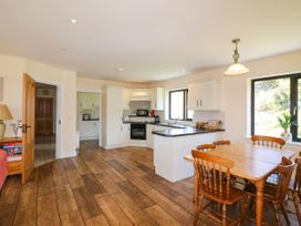 A kitchen and dining area with wooden chairs and table next to windows at Curraha in Lauragh County Kerry
