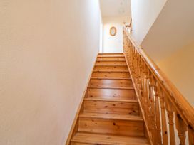 A wooden staircase with a wooden handrail and light walls at Curraha in Lauragh County Kerry
