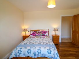 A bedroom with a double bed and floral bedding with two bedside tables and lamps at Curraha in Lauragh County Kerry