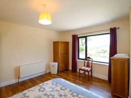 A bedroom with wooden wardrobe chair and chest of drawers near a window with purple curtains at Curraha in Lauragh County Kerry