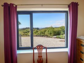 A window with purple curtains and a wooden chair facing outside at Curraha in Lauragh County Kerry
