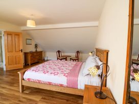 A bedroom with a wooden bed a pink and white quilt and floral lamps at Curraha in Lauragh County Kerry
