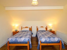 A bedroom with two single beds with blue patterned bedspreads two wooden nightstands with lamps and a radiator on the wall at Curraha in Lauragh County Kerry