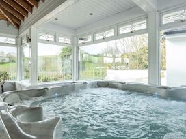 A hot tub surrounded by windows in an indoor pool area at Chapel Green Studio 2 Polgooth