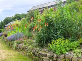 A garden with various flowering plants and a stone wall near a house at Little Cow House in Pontfaen near Chirk