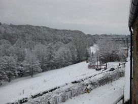 A snowy landscape with trees covered in snow and a fence near a house at Little Cow House in Pontfaen near Chirk