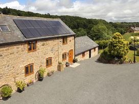 Stone house with solar panels on the roof and potted plants outside near a gravel driveway and garden at Little Cow House in Pontfaen near Chirk