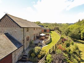 A stone house with a patio and outdoor furniture next to a garden and green fields at Little Cow House in Pontfaen near Chirk