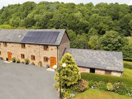 A stone house with solar panels on the roof surrounded by trees and garden Little Cow House Pontfaen near Chirk
