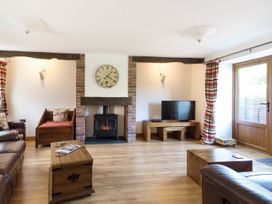 A living room with wooden furniture a fireplace and a television at Little Cow House in Pontfaen near Chirk