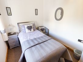 A small bedroom with a single bed bedside table lamp wall mirror and chair at Little Cow House Pontfaen near Chirk